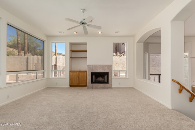 unfurnished living room with light colored carpet, a fireplace, and ceiling fan