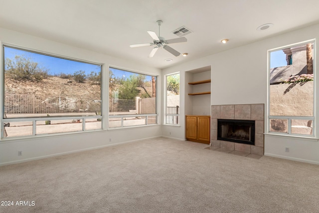 unfurnished living room featuring a healthy amount of sunlight, a fireplace, visible vents, and light colored carpet