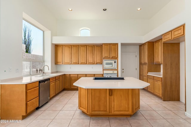 kitchen featuring stainless steel appliances, a sink, light countertops, and a center island