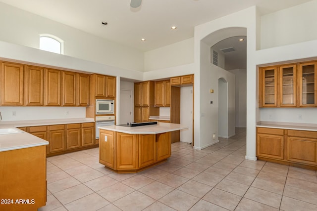 kitchen with brown cabinetry, arched walkways, white appliances, and light countertops