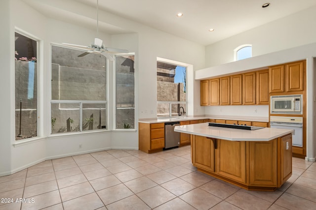 kitchen featuring ceiling fan, a kitchen island, a kitchen bar, light tile patterned floors, and white appliances