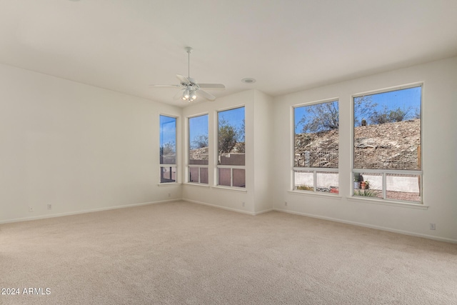 empty room featuring baseboards, ceiling fan, and light colored carpet