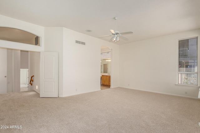 unfurnished room with arched walkways, light carpet, visible vents, a ceiling fan, and vaulted ceiling