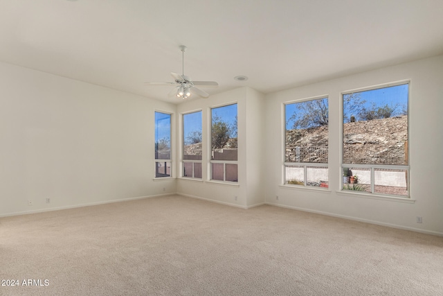 empty room featuring ceiling fan and light colored carpet