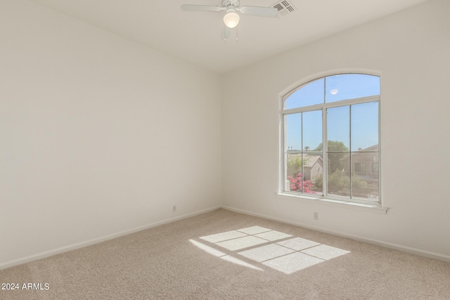 spare room featuring carpet, baseboards, ceiling fan, and a wealth of natural light