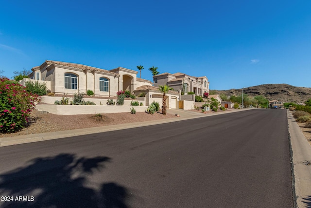 view of front of property with driveway, a tiled roof, an attached garage, a mountain view, and stucco siding