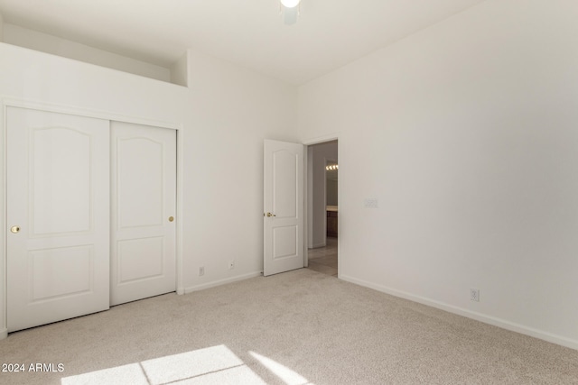 unfurnished bedroom with light colored carpet, a closet, and ceiling fan