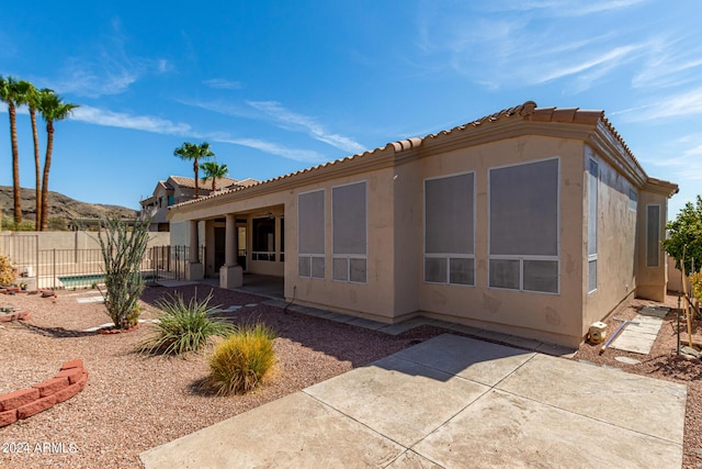 back of house featuring a patio area, a tile roof, fence, and stucco siding