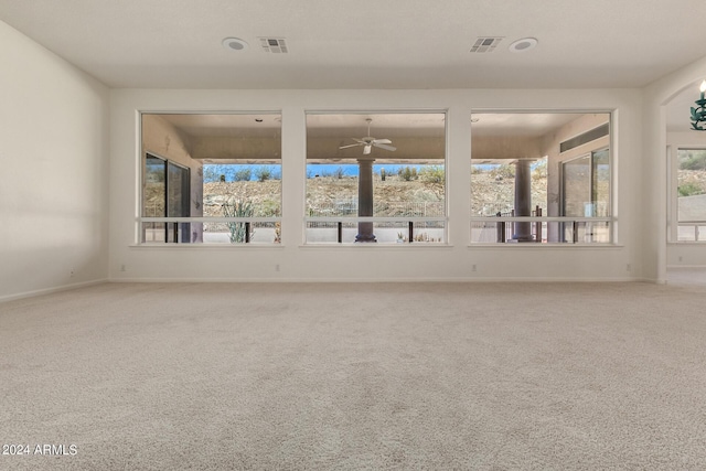 carpeted empty room featuring visible vents, ceiling fan, and baseboards