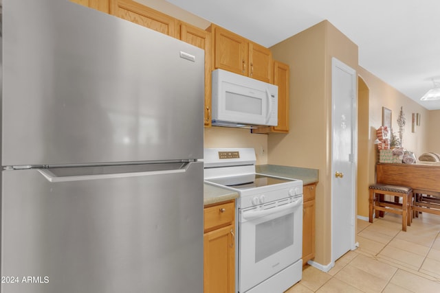 kitchen featuring light tile patterned floors, white appliances, and light brown cabinets