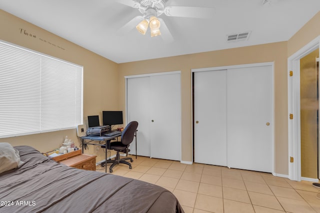 tiled bedroom featuring two closets and ceiling fan