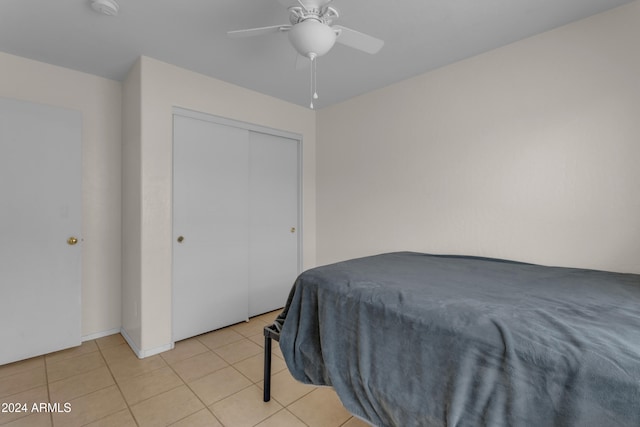 bedroom with light tile patterned floors, a closet, and ceiling fan