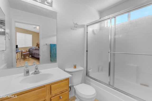 full bathroom featuring vanity, combined bath / shower with glass door, and toilet