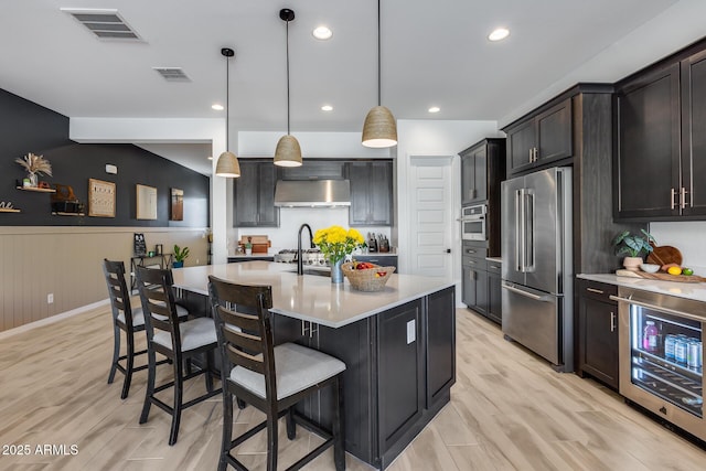 kitchen featuring wine cooler, light countertops, visible vents, appliances with stainless steel finishes, and under cabinet range hood