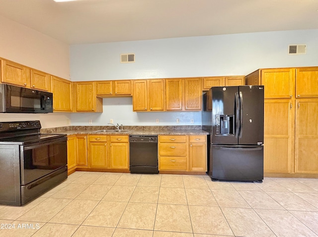 kitchen featuring black appliances, a towering ceiling, sink, and light tile patterned floors