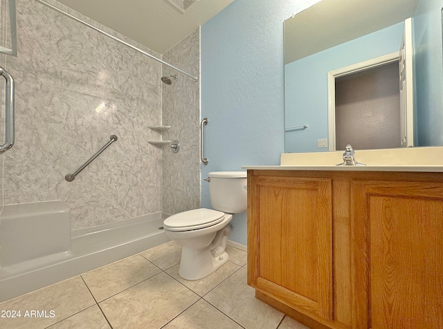 bathroom with tile patterned flooring, a tile shower, vanity, and toilet