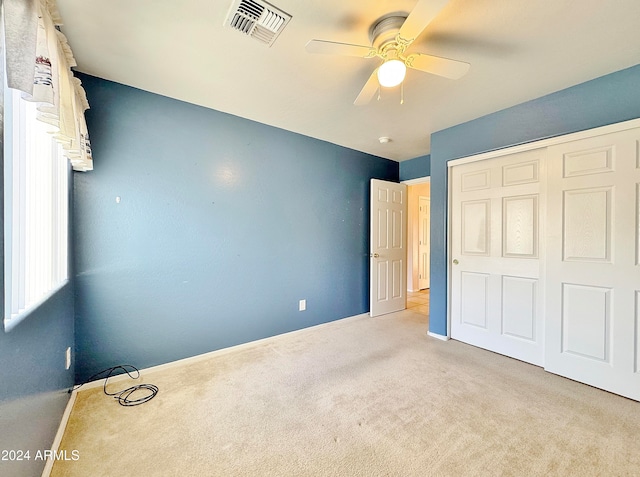 unfurnished bedroom with ceiling fan, a closet, and light carpet