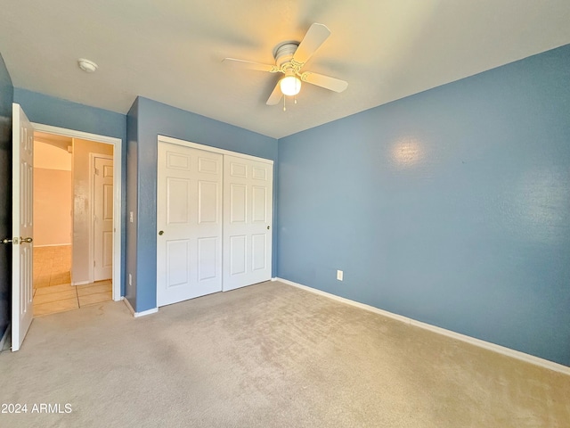 unfurnished bedroom featuring ceiling fan, a closet, and light colored carpet