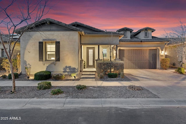 view of front of property featuring concrete driveway, an attached garage, a tile roof, and stucco siding