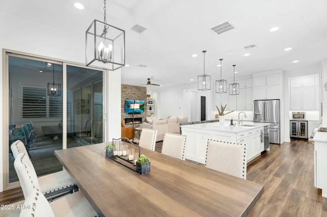 dining room with visible vents, dark wood-style floors, recessed lighting, wine cooler, and a fireplace