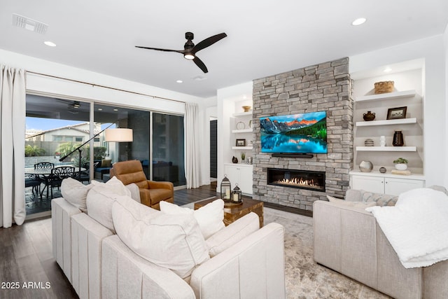 living area featuring built in features, visible vents, wood finished floors, and a ceiling fan