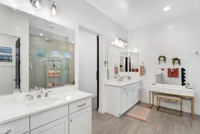 full bathroom with two vanities, baseboards, a stall shower, and a sink