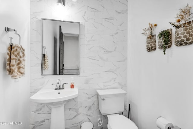 bathroom featuring toilet and tile walls