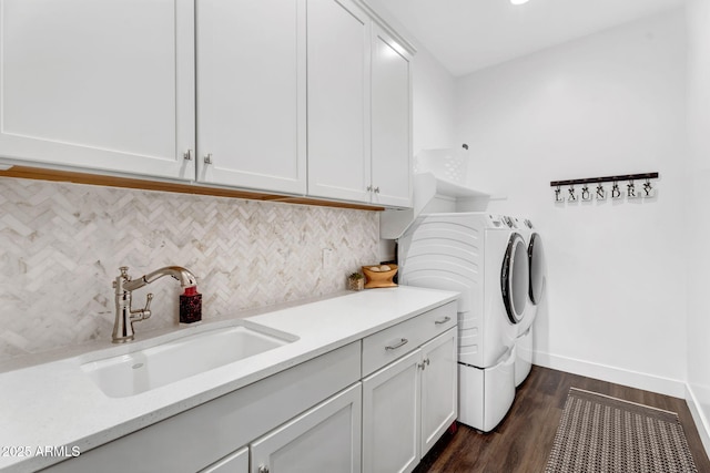 laundry area with dark wood-type flooring, baseboards, washer and dryer, cabinet space, and a sink