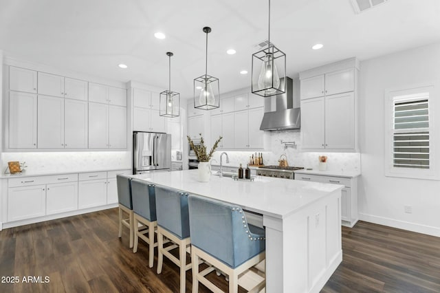 kitchen with white cabinets, wall chimney exhaust hood, and appliances with stainless steel finishes