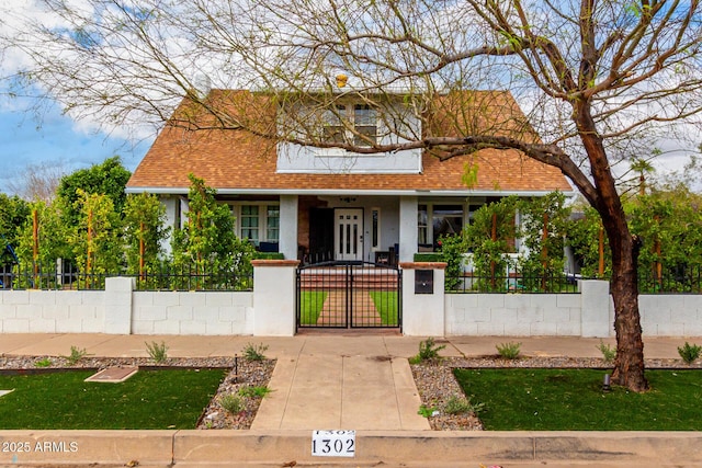 view of front of home with a gate, a porch, stucco siding, a shingled roof, and a fenced front yard