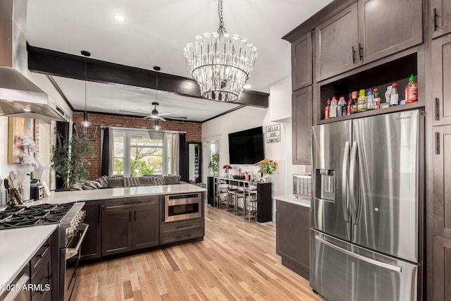 kitchen with dark brown cabinets, brick wall, open floor plan, light countertops, and appliances with stainless steel finishes