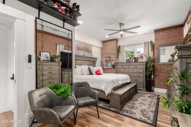 bedroom with wood finished floors, brick wall, and ceiling fan