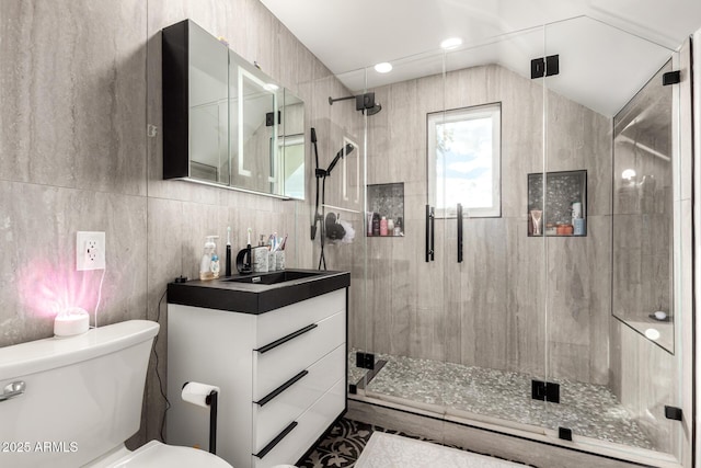 bathroom with a stall shower, toilet, vanity, and lofted ceiling