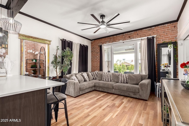 living area featuring ceiling fan, light wood-style flooring, brick wall, and ornamental molding