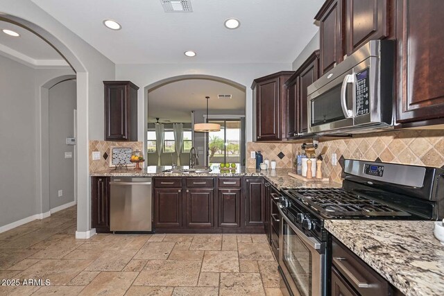 6611 S San Jacinto St, Gilbert, AZ 85298 - kitchen with appliances with stainless steel finishes, a sink, light stone counters, arched walkways, and decorative backsplash