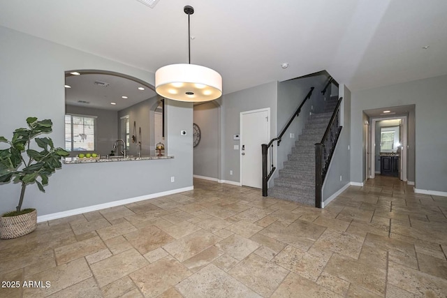 6611 S San Jacinto St, Gilbert, AZ 85298 - unfurnished living room with stone tile flooring, arched walkways, stairs, baseboards, and recessed lighting