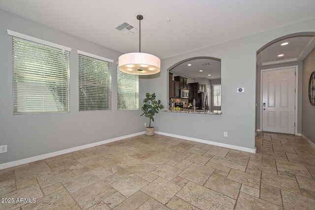6611 S San Jacinto St, Gilbert, AZ 85298 - unfurnished room featuring stone tile floors, baseboards, arched walkways, and recessed lighting