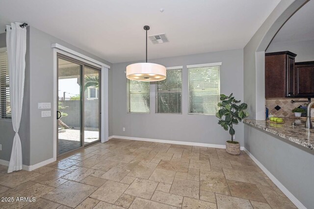 6611 S San Jacinto St, Gilbert, AZ 85298 - unfurnished dining area featuring stone tile floors, plenty of natural light, and baseboards