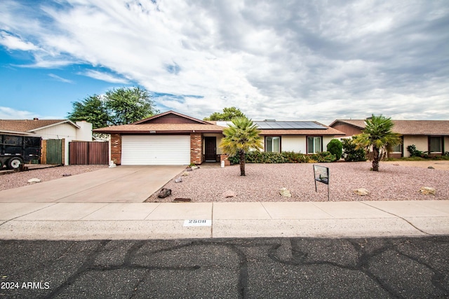 single story home featuring solar panels and a garage