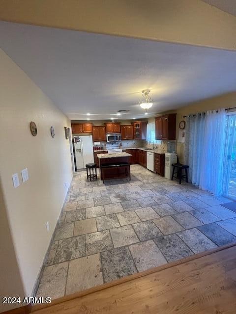 kitchen featuring a kitchen island, sink, white appliances, a kitchen bar, and decorative backsplash