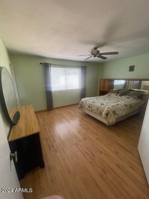 bedroom with a textured ceiling, ceiling fan, and light hardwood / wood-style floors