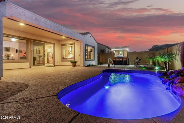 pool at dusk featuring a patio