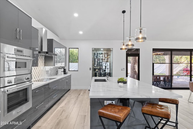 kitchen with a breakfast bar, light wood-type flooring, a wealth of natural light, and wall chimney range hood