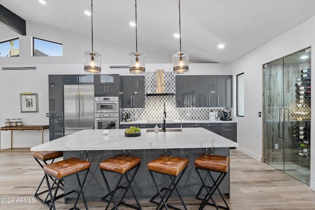 kitchen featuring a kitchen bar, lofted ceiling, hanging light fixtures, and stainless steel appliances