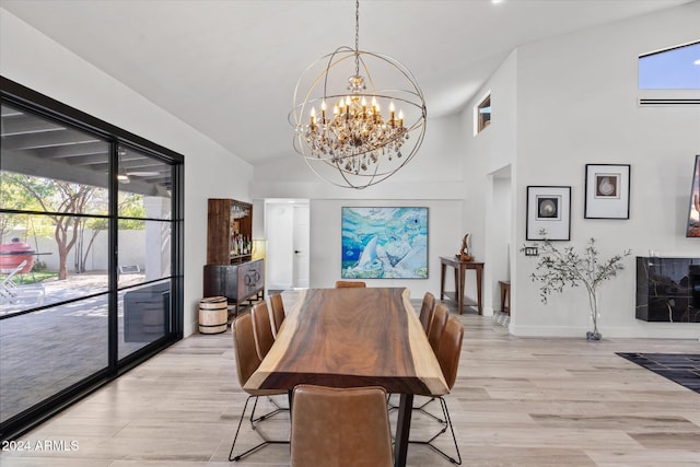 dining space featuring high vaulted ceiling, light hardwood / wood-style floors, and a notable chandelier