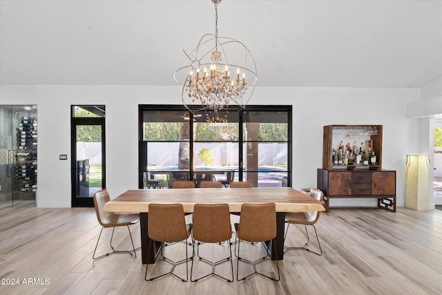 dining area with light wood-type flooring and a notable chandelier