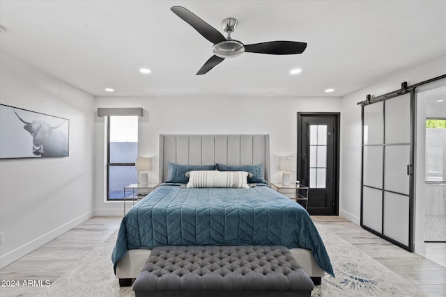 bedroom featuring light wood-type flooring, a barn door, and multiple windows