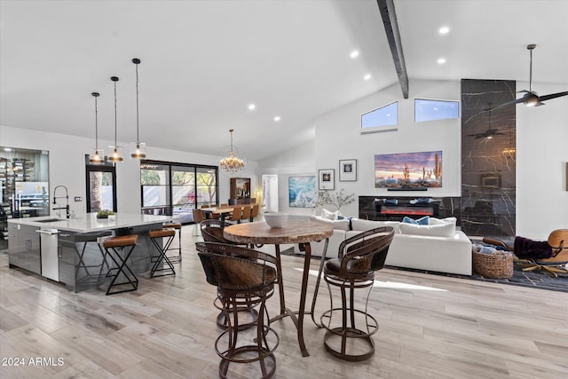 dining area with vaulted ceiling with beams, sink, light hardwood / wood-style floors, and ceiling fan with notable chandelier