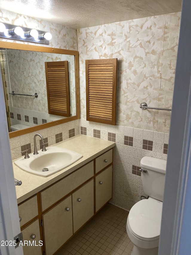 2569 W Berridge Ln Unit D-115, Phoenix, AZ 85017 - bathroom with wallpapered walls, tile patterned floors, toilet, vanity, and tile walls