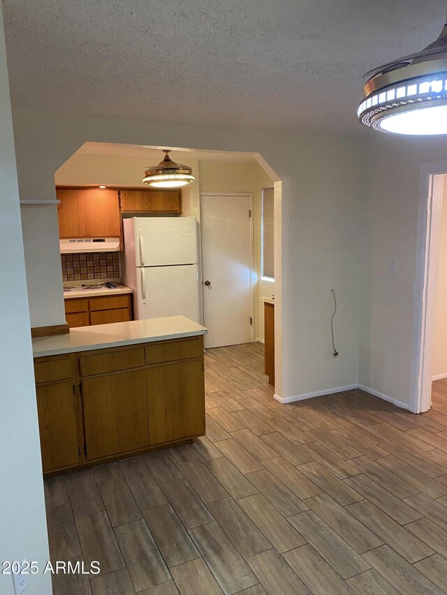 2569 W Berridge Ln Unit D-115, Phoenix, AZ 85017 - kitchen with under cabinet range hood, wood finished floors, light countertops, and freestanding refrigerator